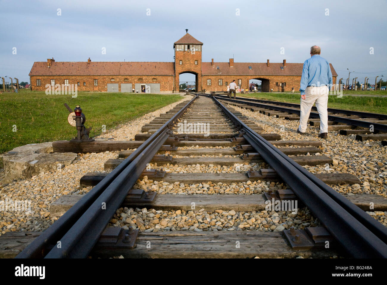 Tourist ispeziona le linee ferroviarie in prossimità dell' ingresso principale a Birkenau (Auschwitz II - Birkenau) nazista di morte nel campo di Oswiecim, Polonia Foto Stock