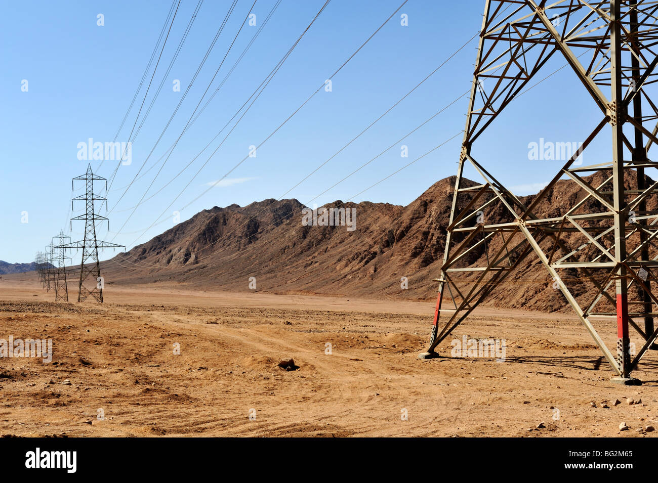 Riga di linee elettriche di alimentazione attraversando il paesaggio del deserto del Sinai, Egitto Foto Stock