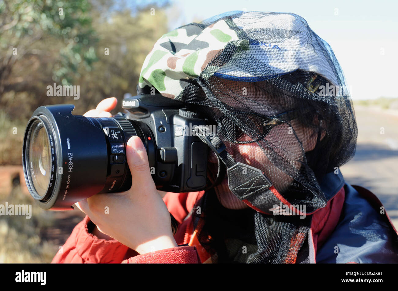 Una ragazza giovane turista indossando una zanzariera a rete sopra il suo volto come protezione contro sciami di inserti nel centro rosso dell'Australia Foto Stock