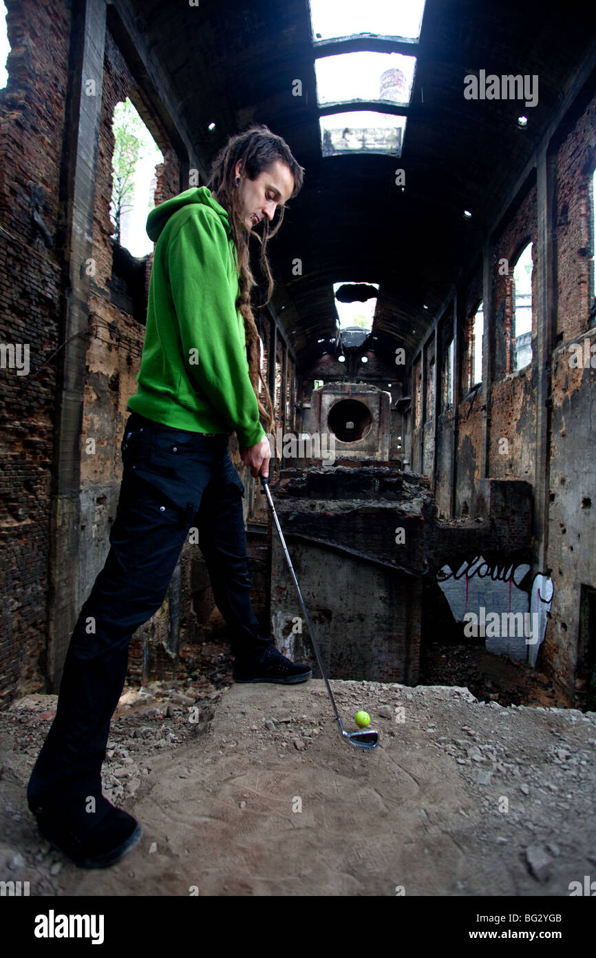 Giovane con dreadlocks giocando fuori di golf nel post-industriale hall. Foto Stock