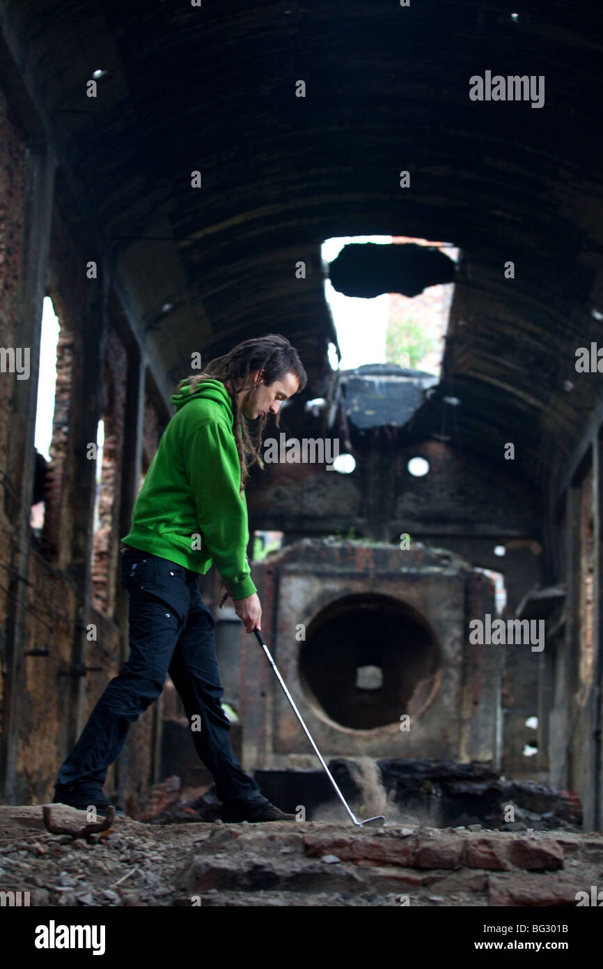 Giovane con dreadlocks giocando fuori di golf nel post-industriale hall. Foto Stock