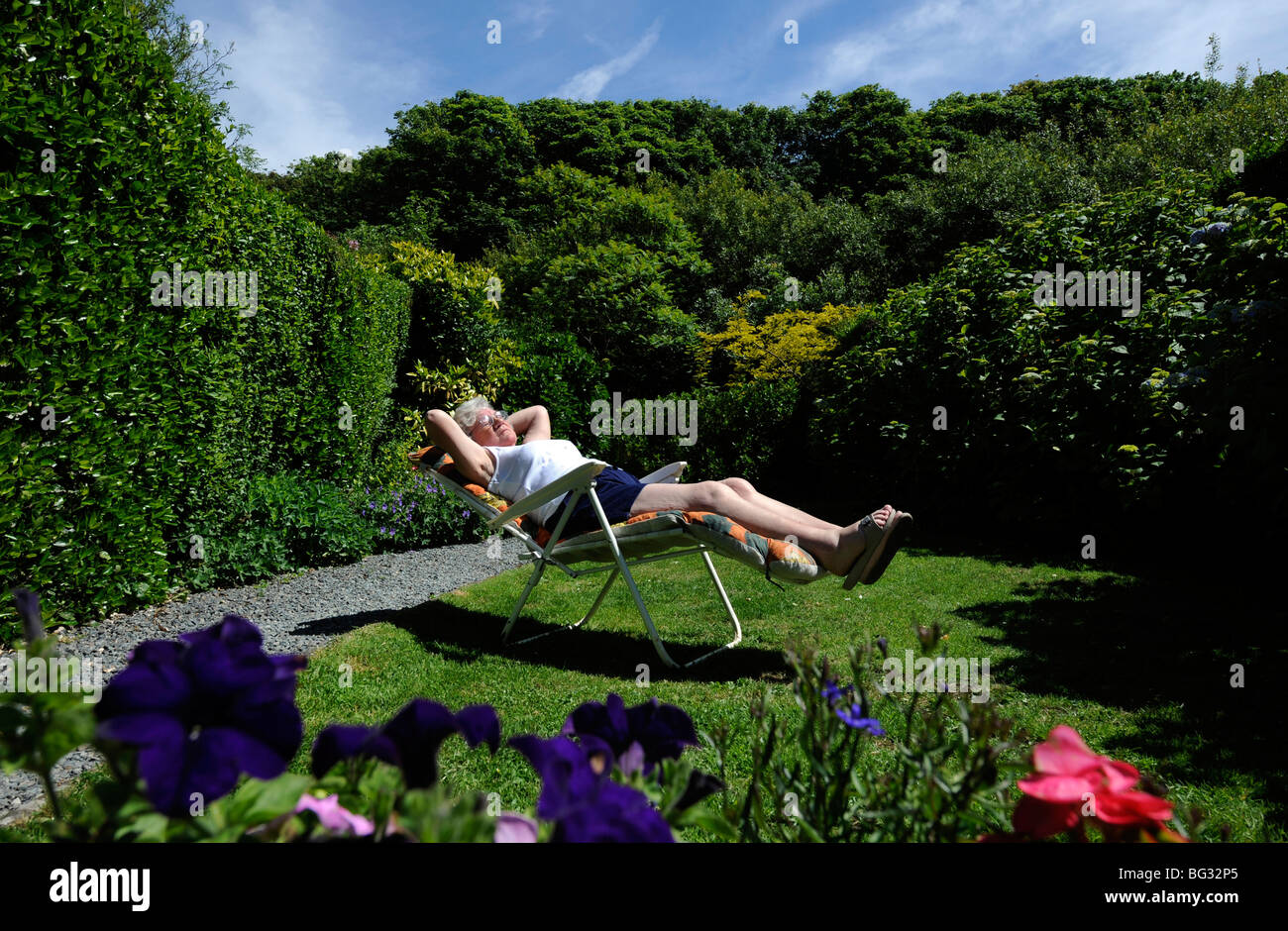 La vecchiaia LADY PENSIONATO GODE DI PENSIONE di prendere il sole nel giardino Inglese UK Foto Stock