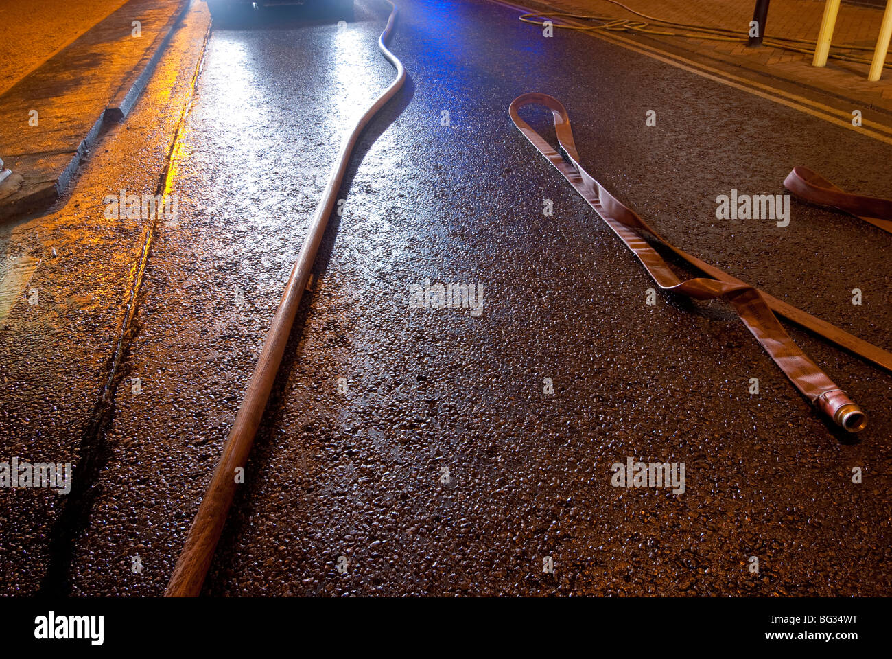 Tubo antincendio su strada bagnata nel buio di notte Foto Stock