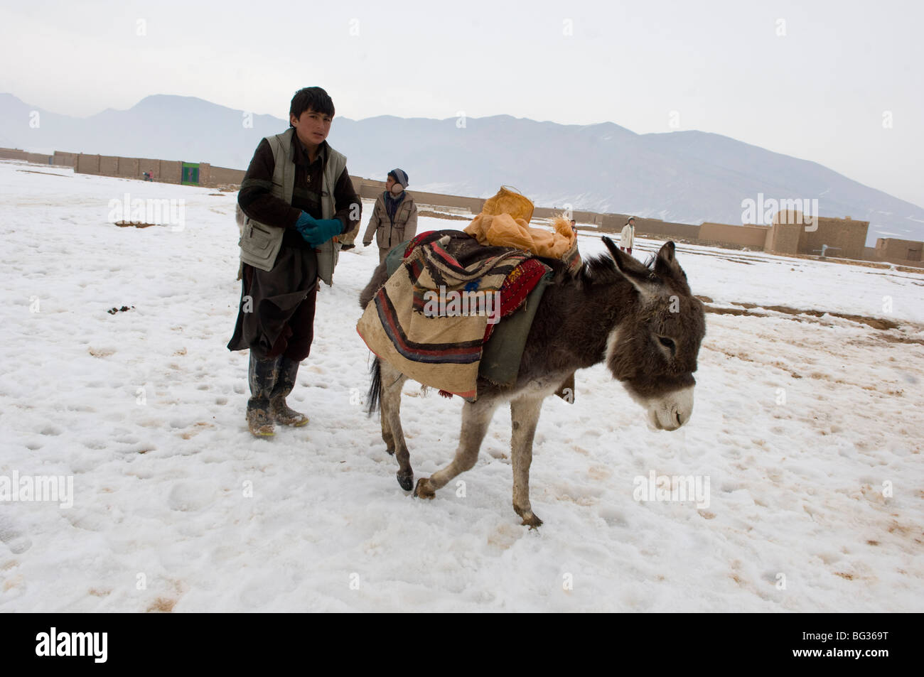 Poveri famiglie afghane ricevere il freddo di forniture di soccorso per aiutarli in inverno severo nel nord dell'Afghanistan. Foto Stock