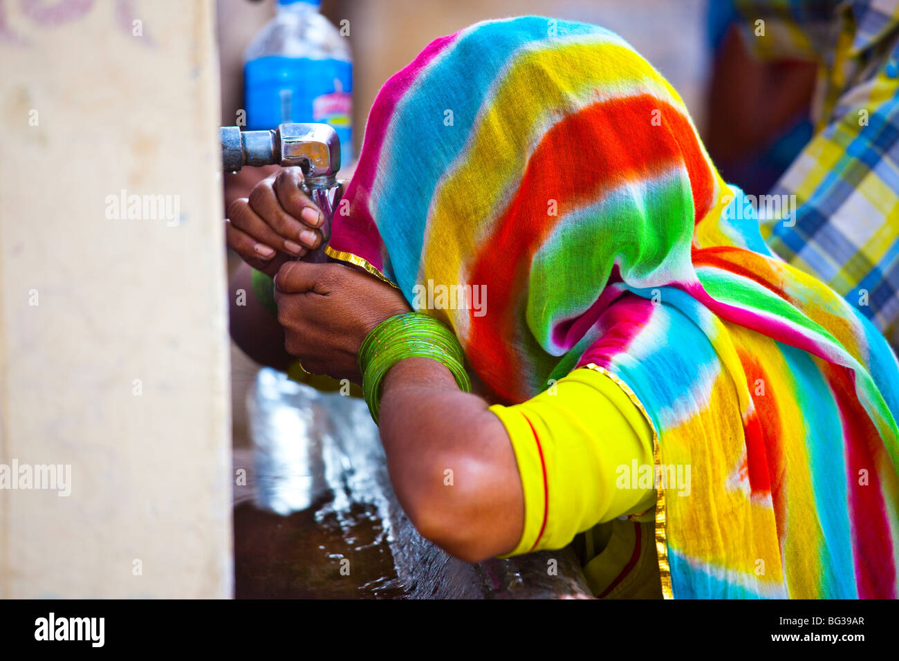 Donna velata di bere da un rubinetto durante il cammello Mela in Pushkar India Foto Stock