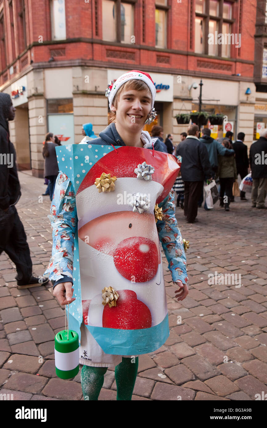 Regno Unito, Inghilterra, Manchester, Market Street, giovane studente maschio vestito di carta natalizia costume per raccogliere per la carità Foto Stock
