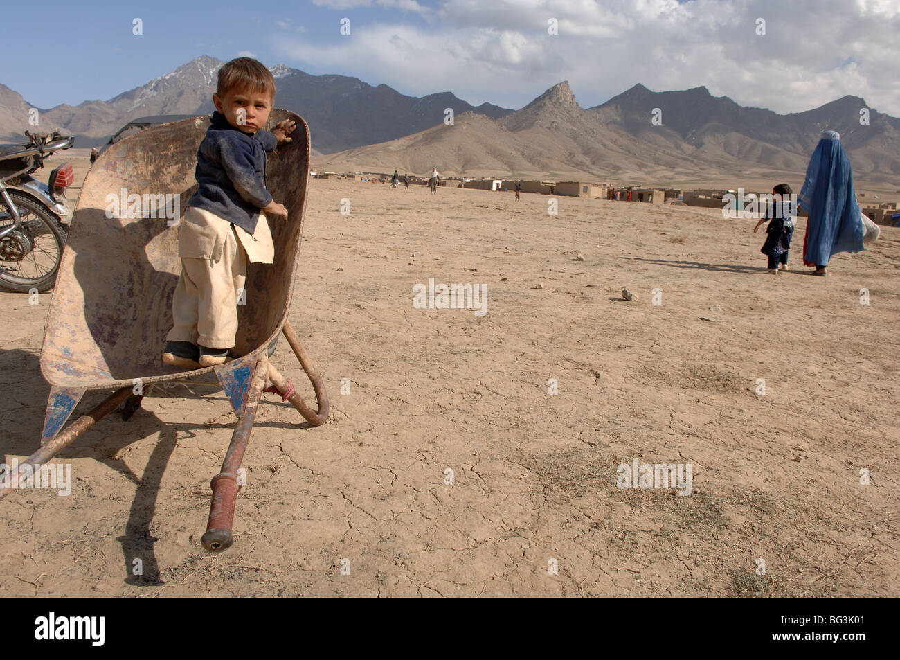 Afghan ragazzo seduto in una ruota di barrow in Bagram, Afghanistan. Foto Stock