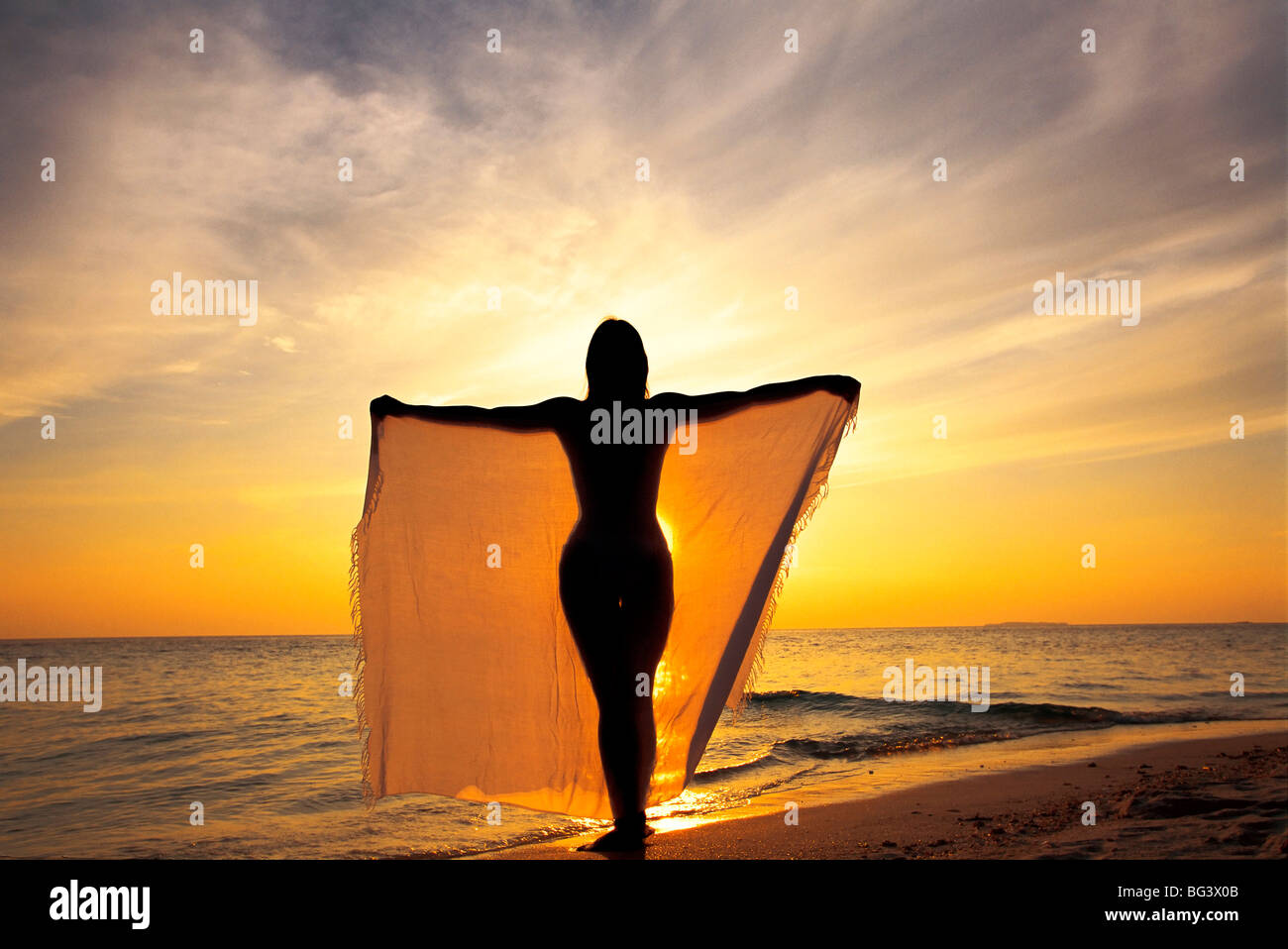 Una donna su una spiaggia al tramonto, Maldive, Oceano Indiano, Asia Foto Stock
