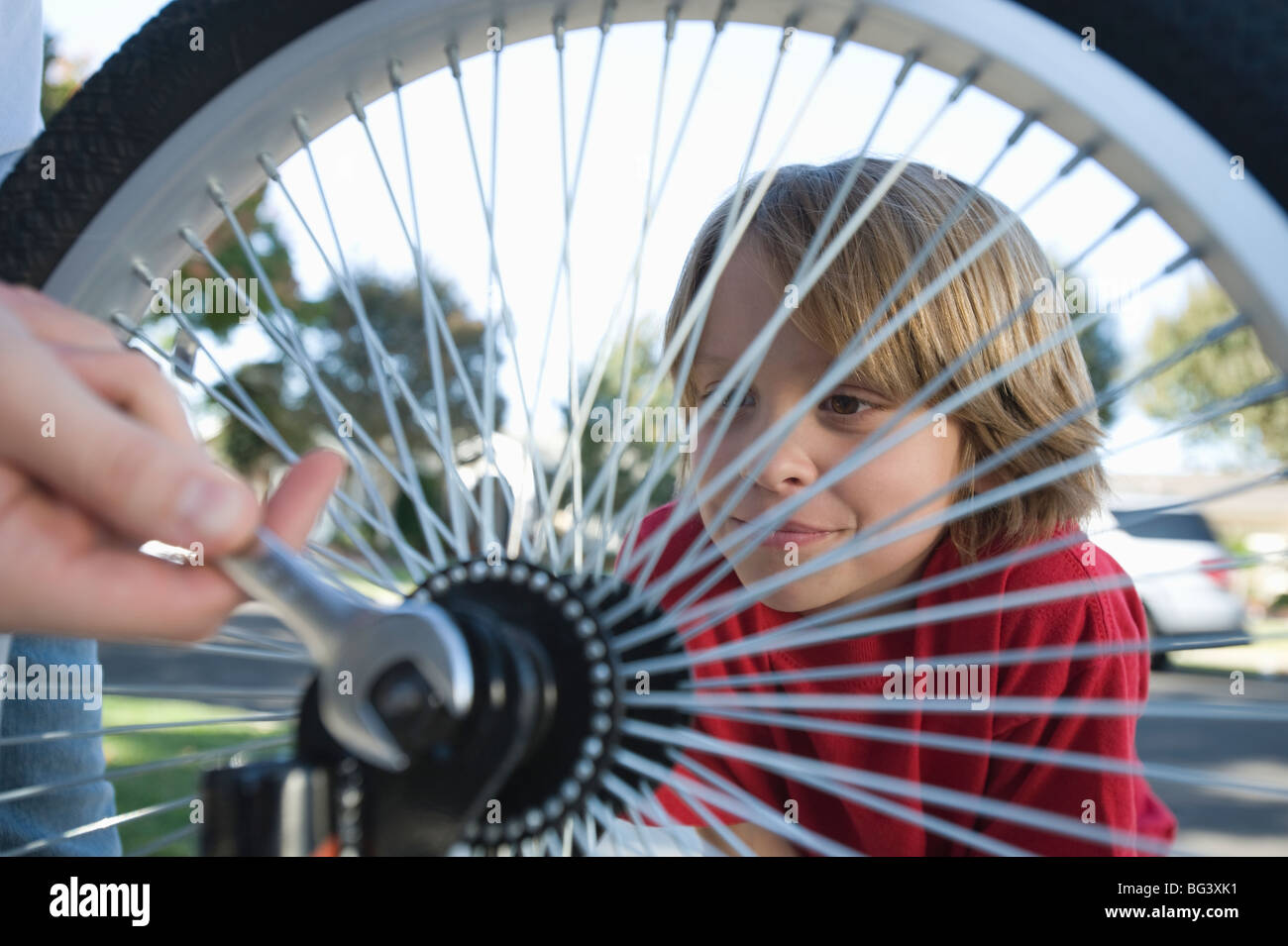 Ragazzo guardando padre fissare il pneumatico di una bicicletta Foto Stock