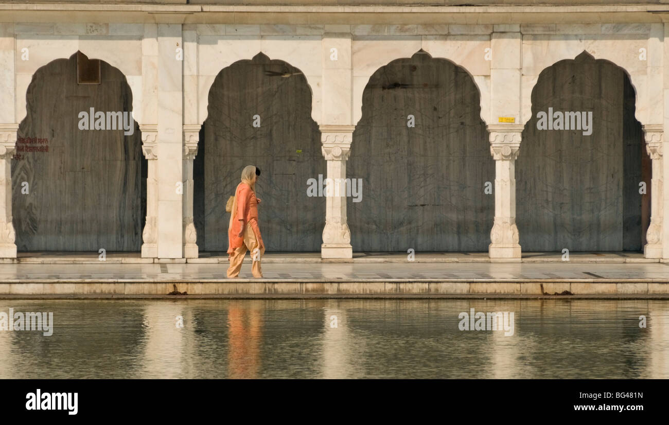 Tradizionalmente Vestiti donna camminando lungo una delle piscine al Bangla Sahib tempio sikh di Delhi, India, Asia Foto Stock