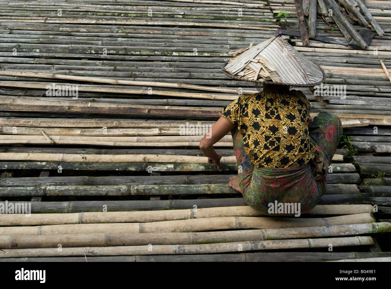 Iban tribeswoman rammendo bamboo longhouse veranda Piano, Lemanak Fiume Sarawak, Malaysian Borneo, Malaysia, Asia Foto Stock