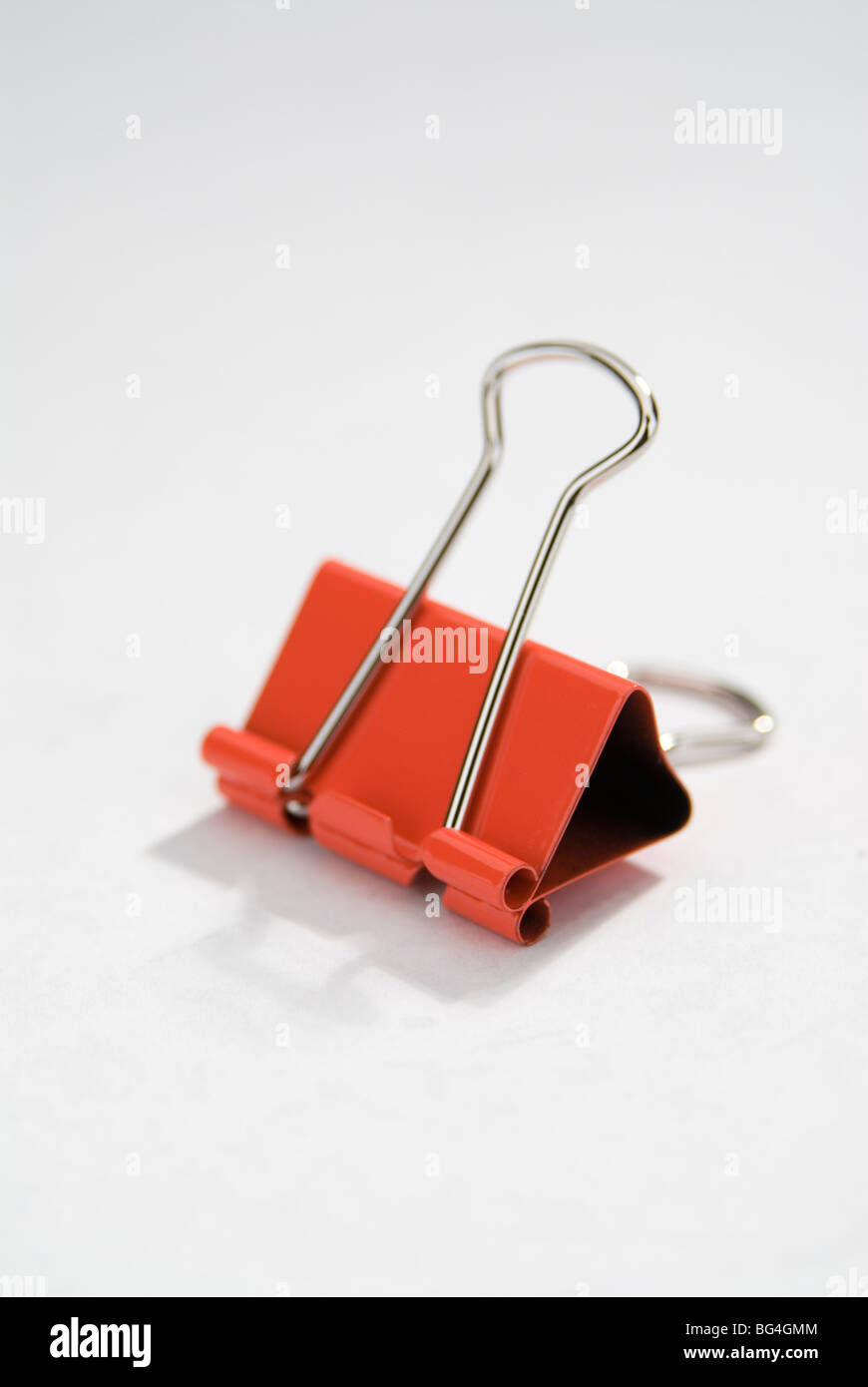 Rosso clip legante su uno sfondo bianco. Foto Stock