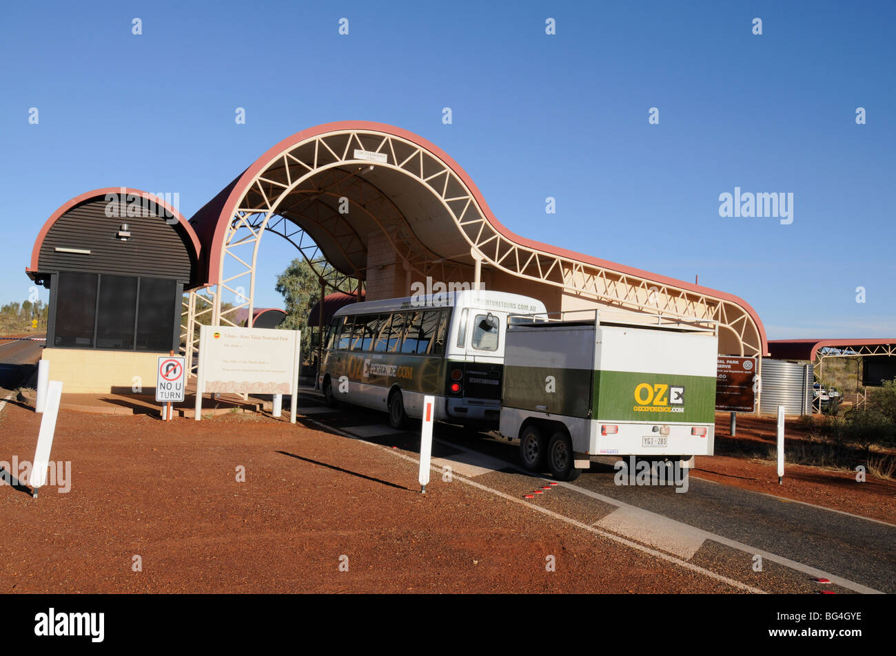 Un turista mini bus si ferma al casello autostradale presso l'entrata principale dell'Uluru-Kata Tjuta National Park in Australia Foto Stock