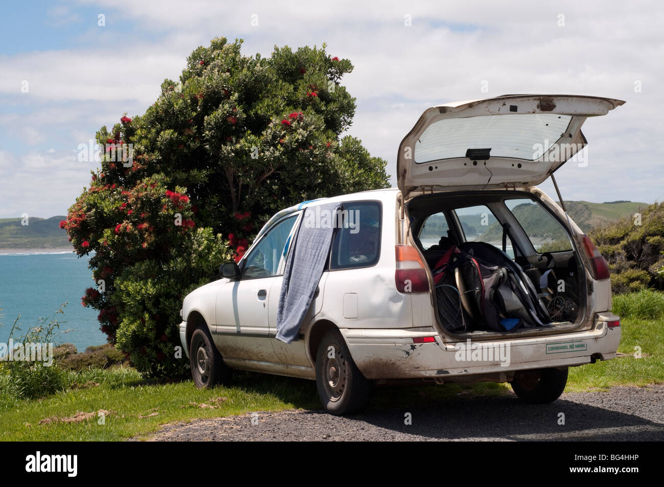 Stazione parcheggiata carro pieno di tavole da surf guardando oltre oceano, prese a Raglan, Nuova Zelanda Foto Stock