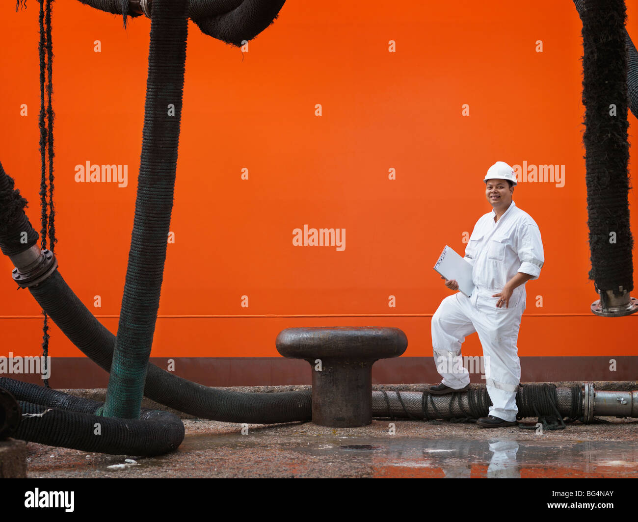 Un autorità portuale lavoratore ispezione di una nave da trasporto di tubi del combustibile. Foto Stock