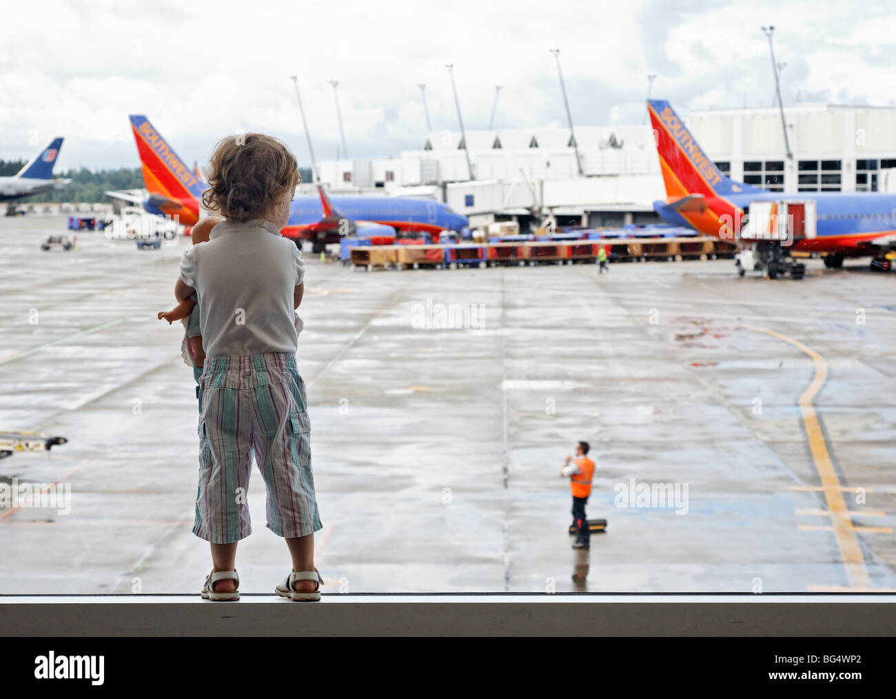 Bambina con bambola guarda gli aerei in aeroporto, Sea Tac, Seattle, Washington, Stati Uniti d'America Foto Stock