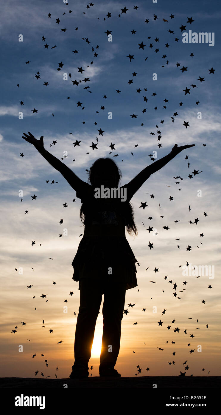 Silhouette di una giovane ragazza indiana gettando stelle al tramonto. India Foto Stock