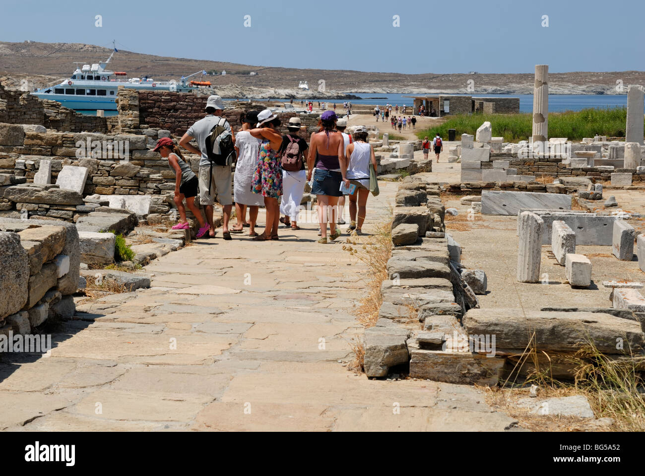 I turisti sono tornare indietro a piedi per il tour in barca. Ci vorranno 2-3 ore per visitare tutte le principali caratteristiche degli antichi Delos. Foto Stock