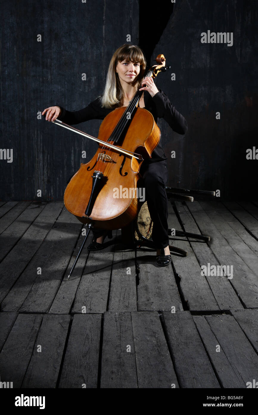 Bella violoncello musicista sul muro grigio sfondo Foto Stock