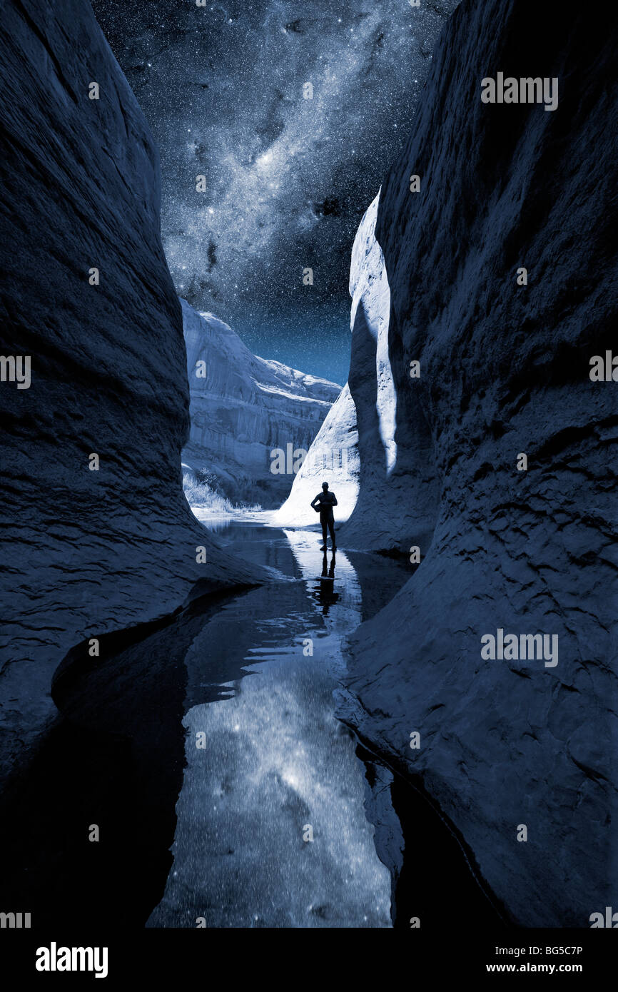 Un uomo che passeggia in un canyon di notte con la Via Lattea Foto Stock