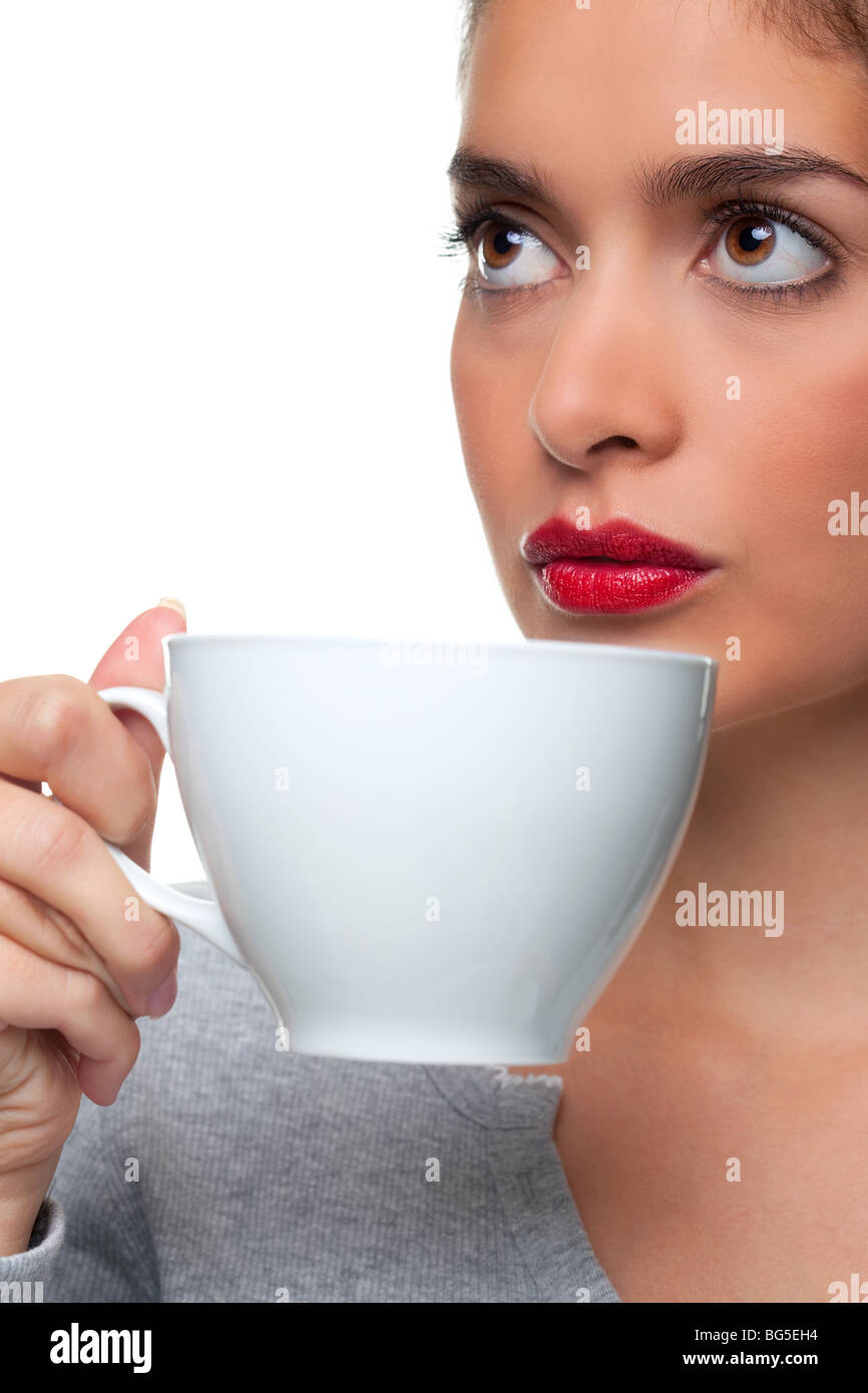 Donna che mantiene un tazza bianca circa per bere un tè come lei sta pensando a qualcosa, sfondo bianco. Foto Stock