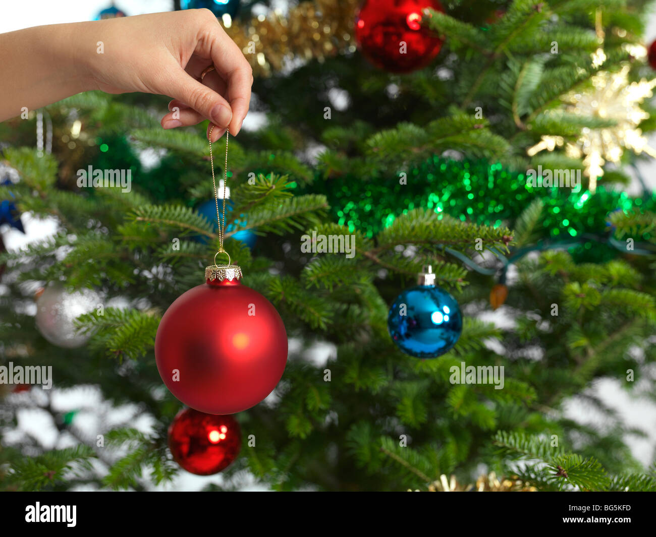 Donna che mantiene ornamento di Natale in una mano la decorazione di un albero di Natale Foto Stock