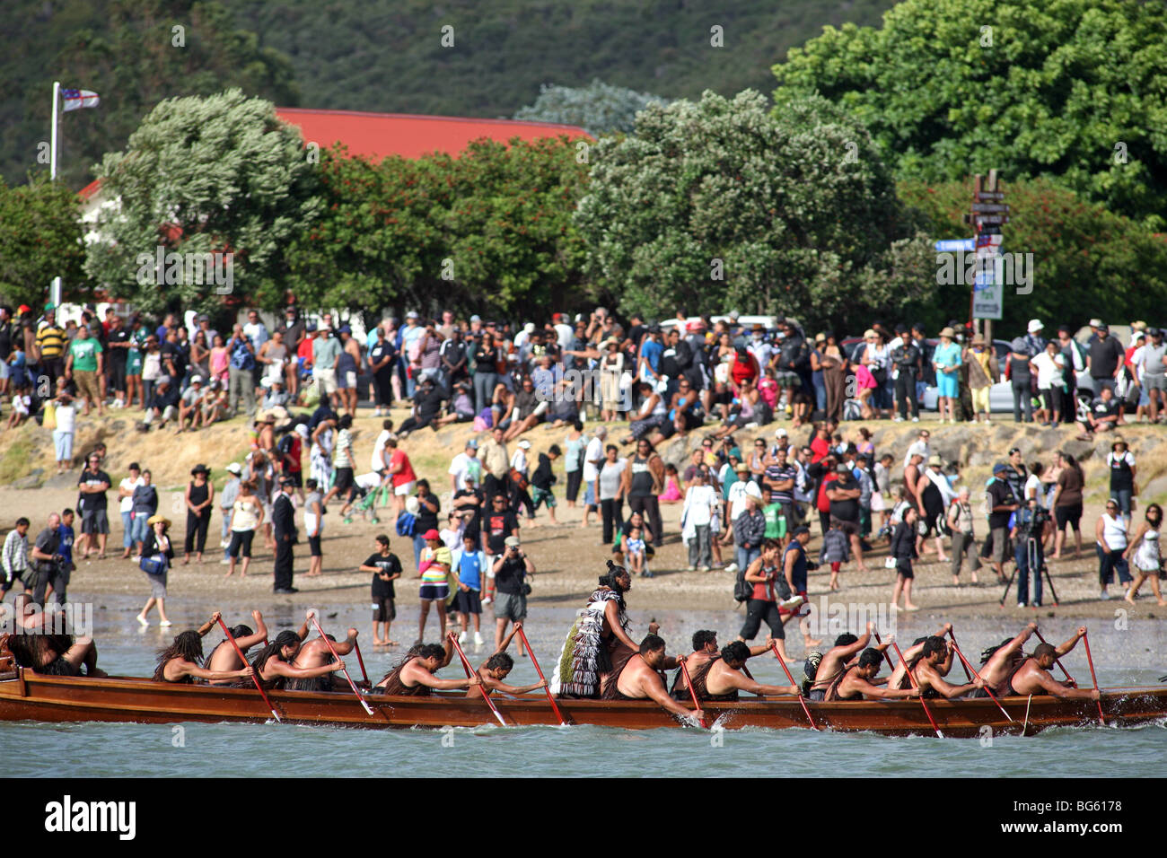 Un Waka Taua (canoe da guerra) passa spettatori su Te Ti Bay durante il Waitangi Day celebrazioni, Nuova Zelanda Foto Stock