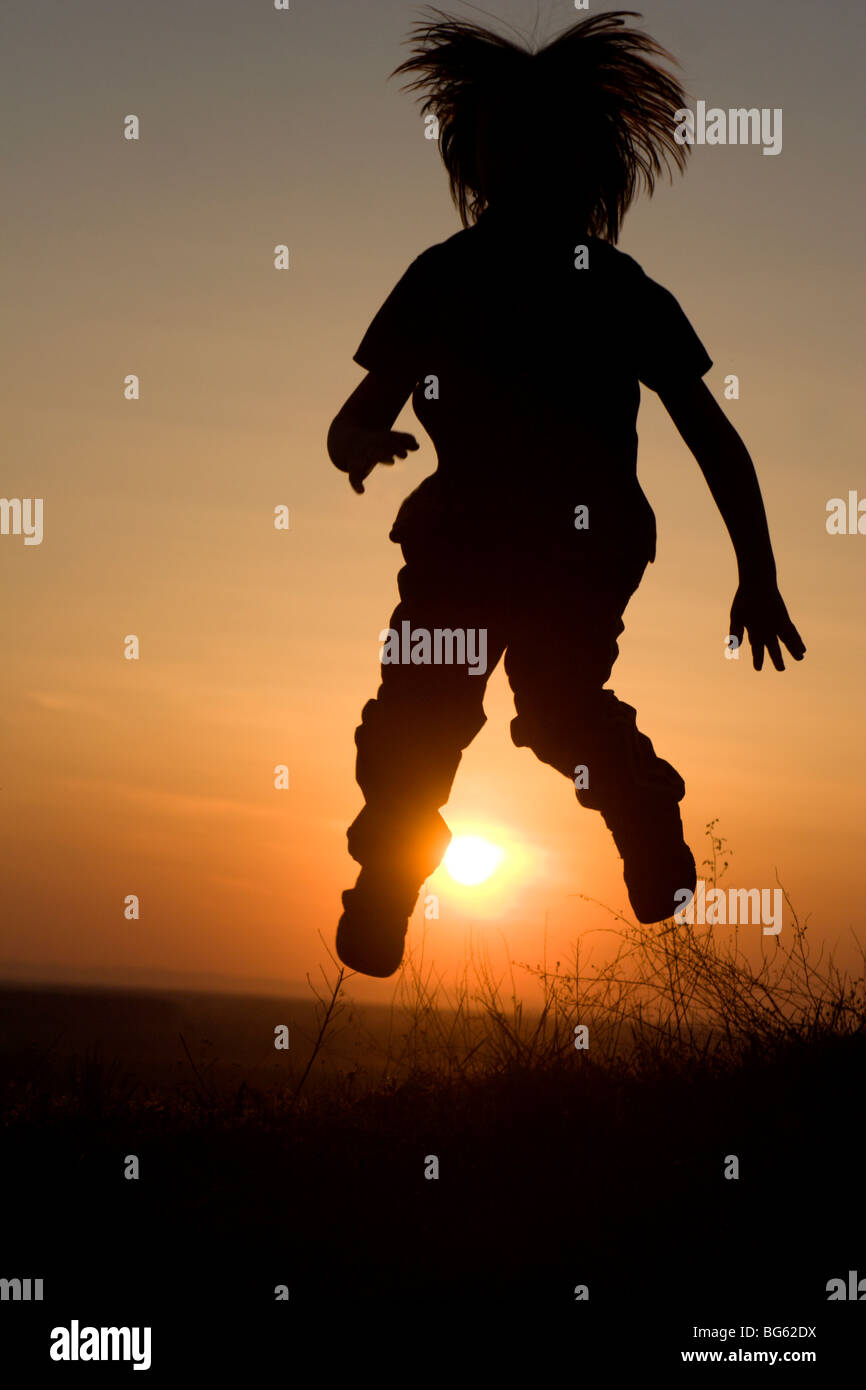 Salto della bambina in sunset - silhouette Foto Stock