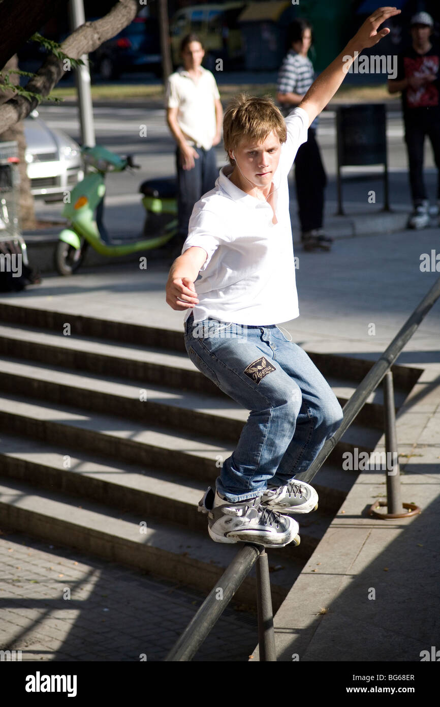 Il giovane si esibisce in trucchi di skate in linea espressivi su una ringhiera di Barcellona Spagna Foto Stock