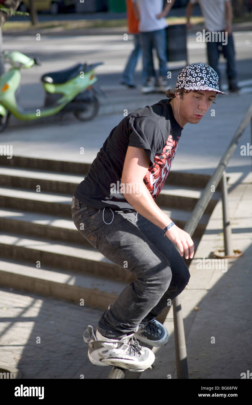 Il giovane si esibisce in trucchi di skate in linea espressivi su una ringhiera di Barcellona Spagna Foto Stock