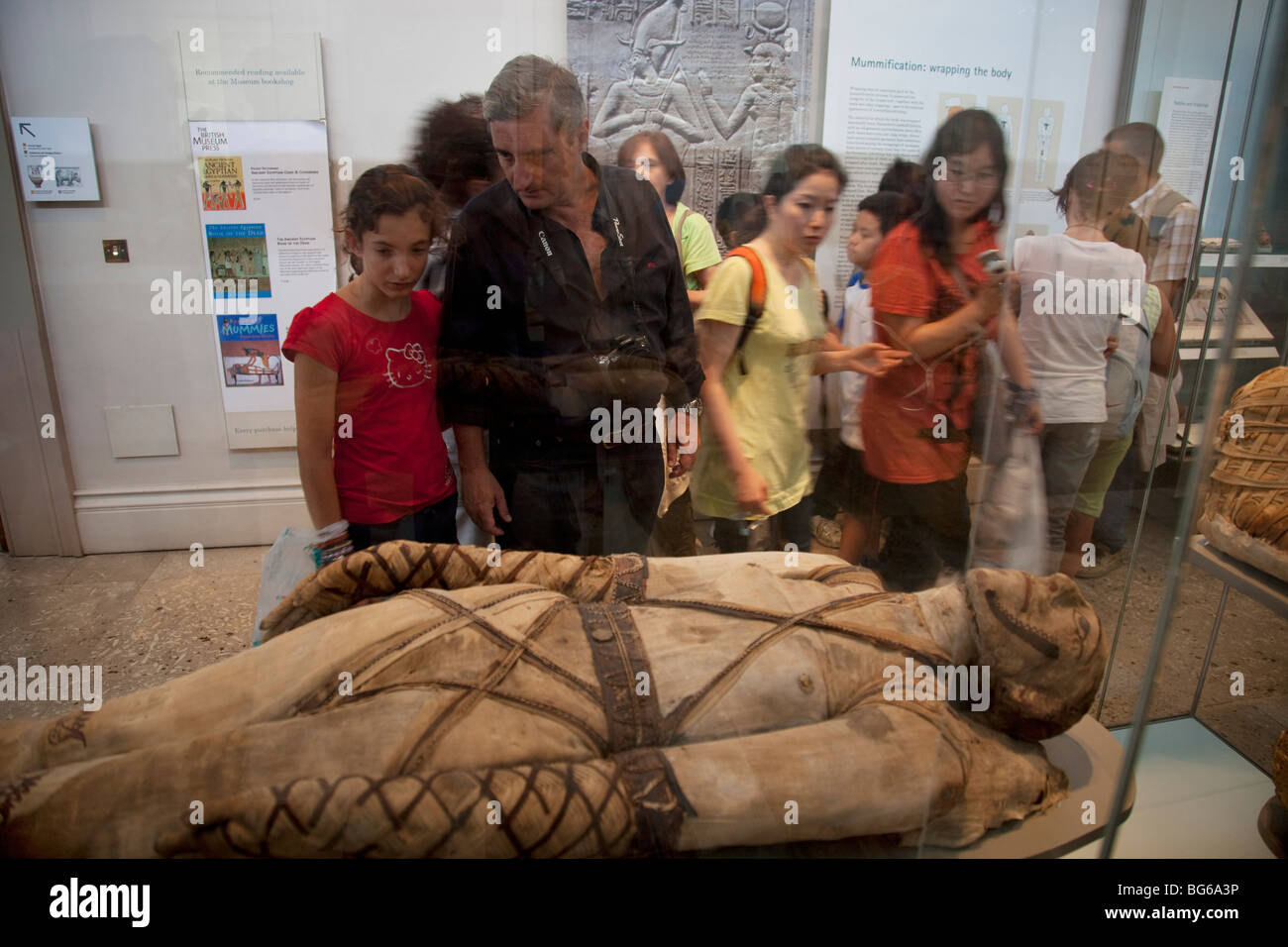 Il British Museum di Londra. I visitatori guardano in scatole di vetro contenente antiche mummie da figure. Foto Stock