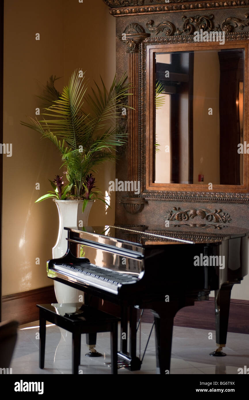 Baby grand piano con un grande specchio e vaso in background Foto Stock