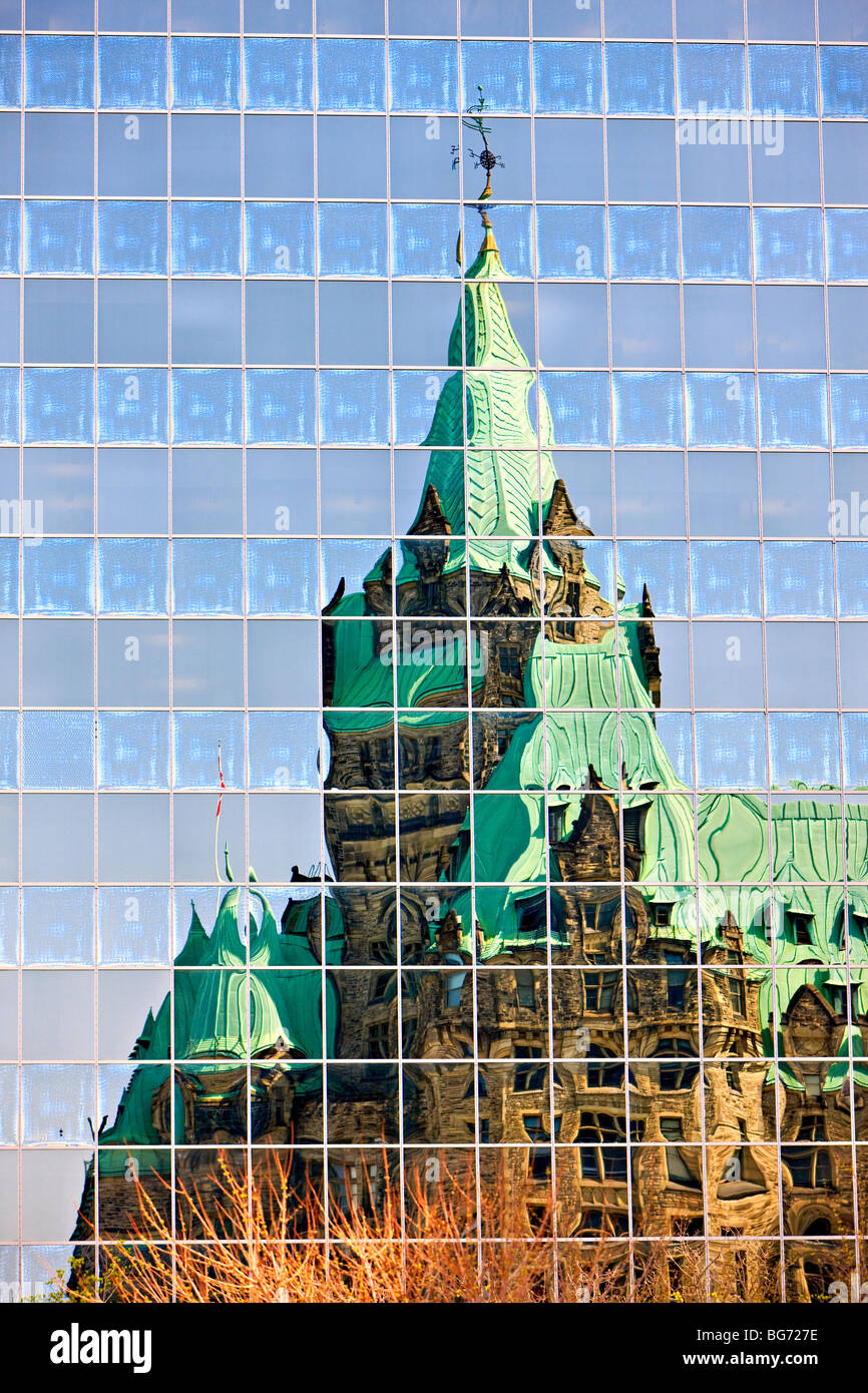 Le riflessioni della Confederazione edificio nelle finestre di un edificio moderno nella città di Ottawa, Ontario, Canada. Foto Stock