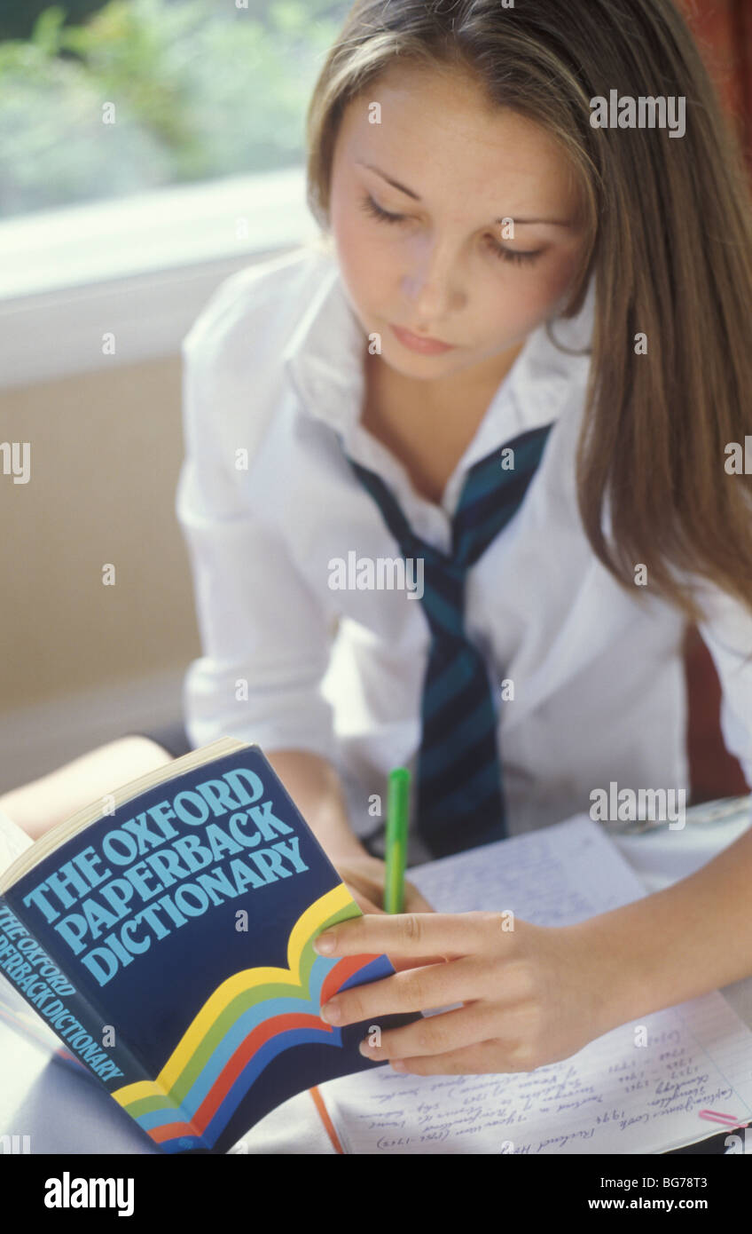 Scuola ragazza utilizzando un dizionario per eseguire i suoi compiti Foto Stock