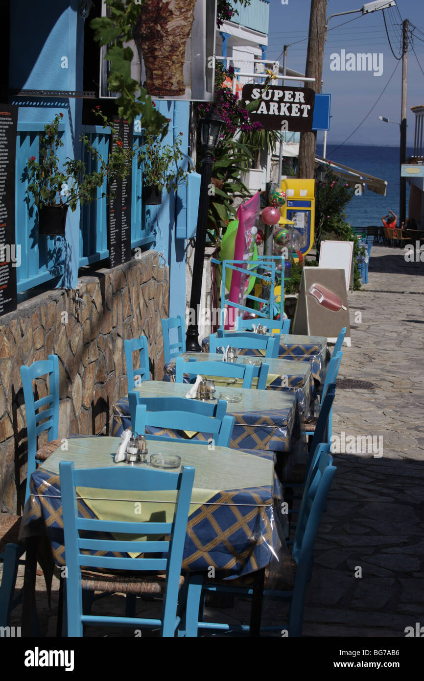 Strade strette attraverso la graziosa cittadina turistica di Agios Nikitis, Lefkas, Grecia. Tipicamente greco ristorante all'aperto. Foto Stock