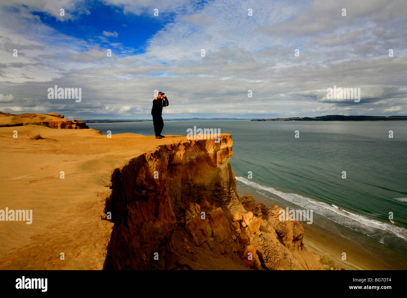 Un uomo scatta una fotografia da aa eroso capezzagna a nord Kiapara capi Nuova Zelanda Foto Stock