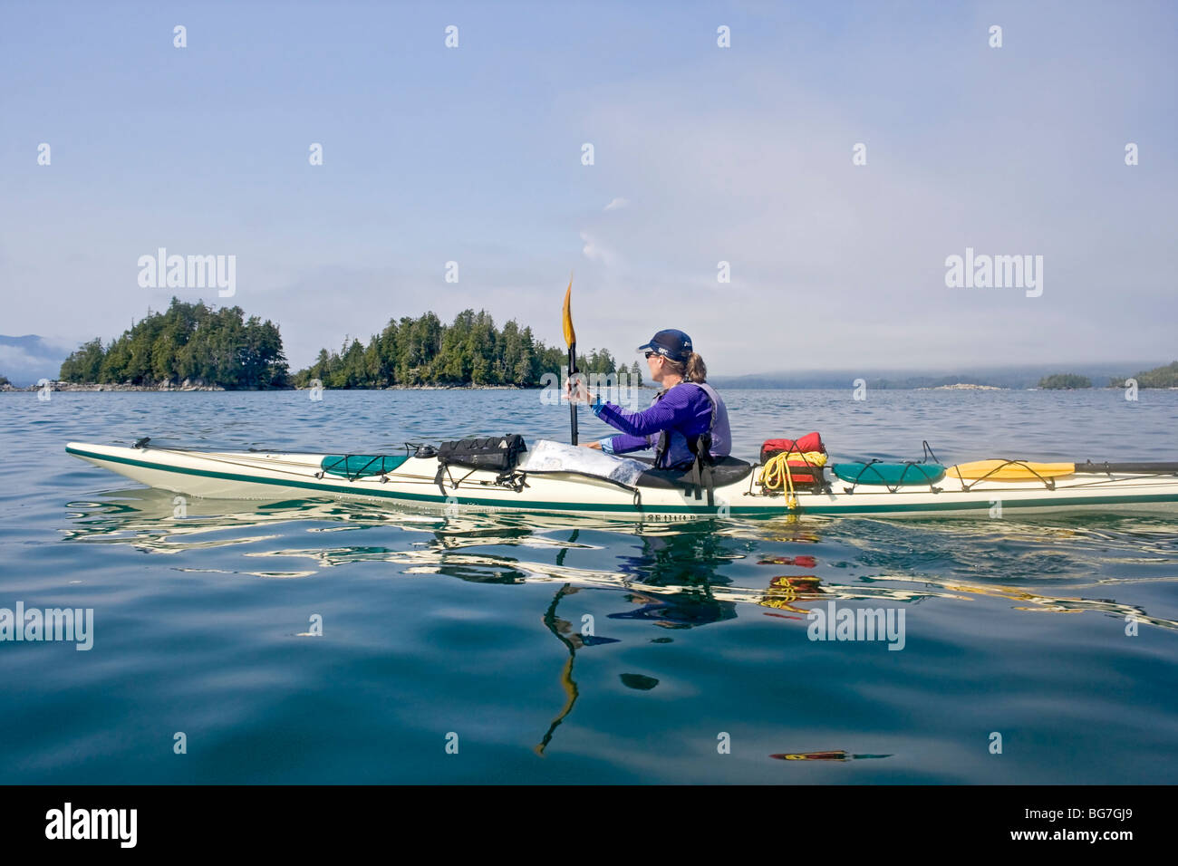 Donna pagaie kayak nelle rotte delle isole del gruppo del Pacific Rim National Park sulla costa occidentale dell'isola di Vancouver, Canada. Foto Stock