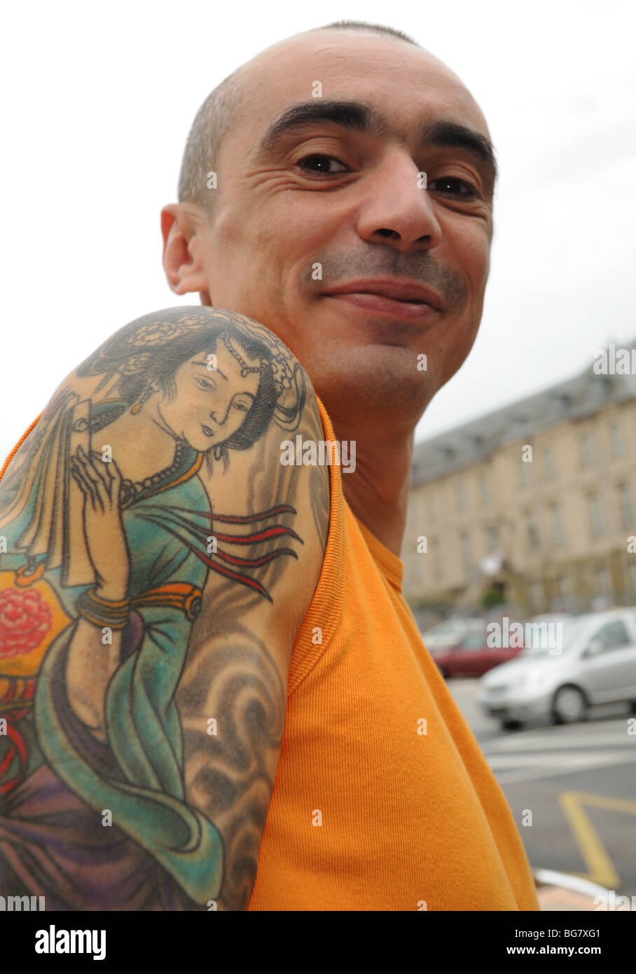 Francese mostra con orgoglio il suo tatuaggio di un elaborato oriental lady sulla sua spalla Foto Stock