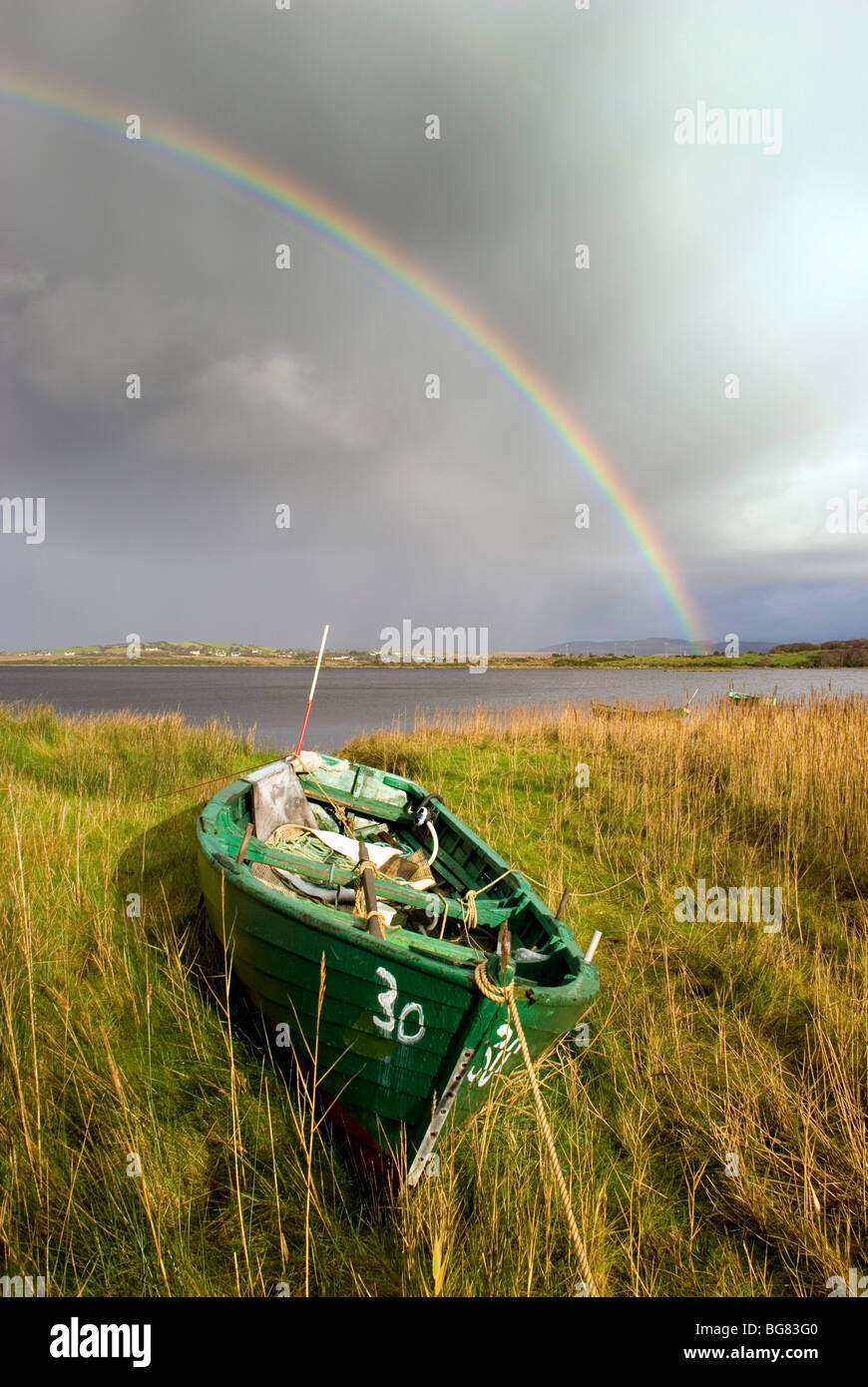 Pesca in legno barca tirata onshore con un arcobaleno nel cielo Foto Stock