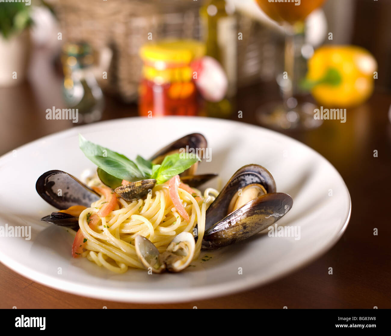 Italiano gli spaghetti con le cozze e basilico su un tavolo di legno Foto Stock