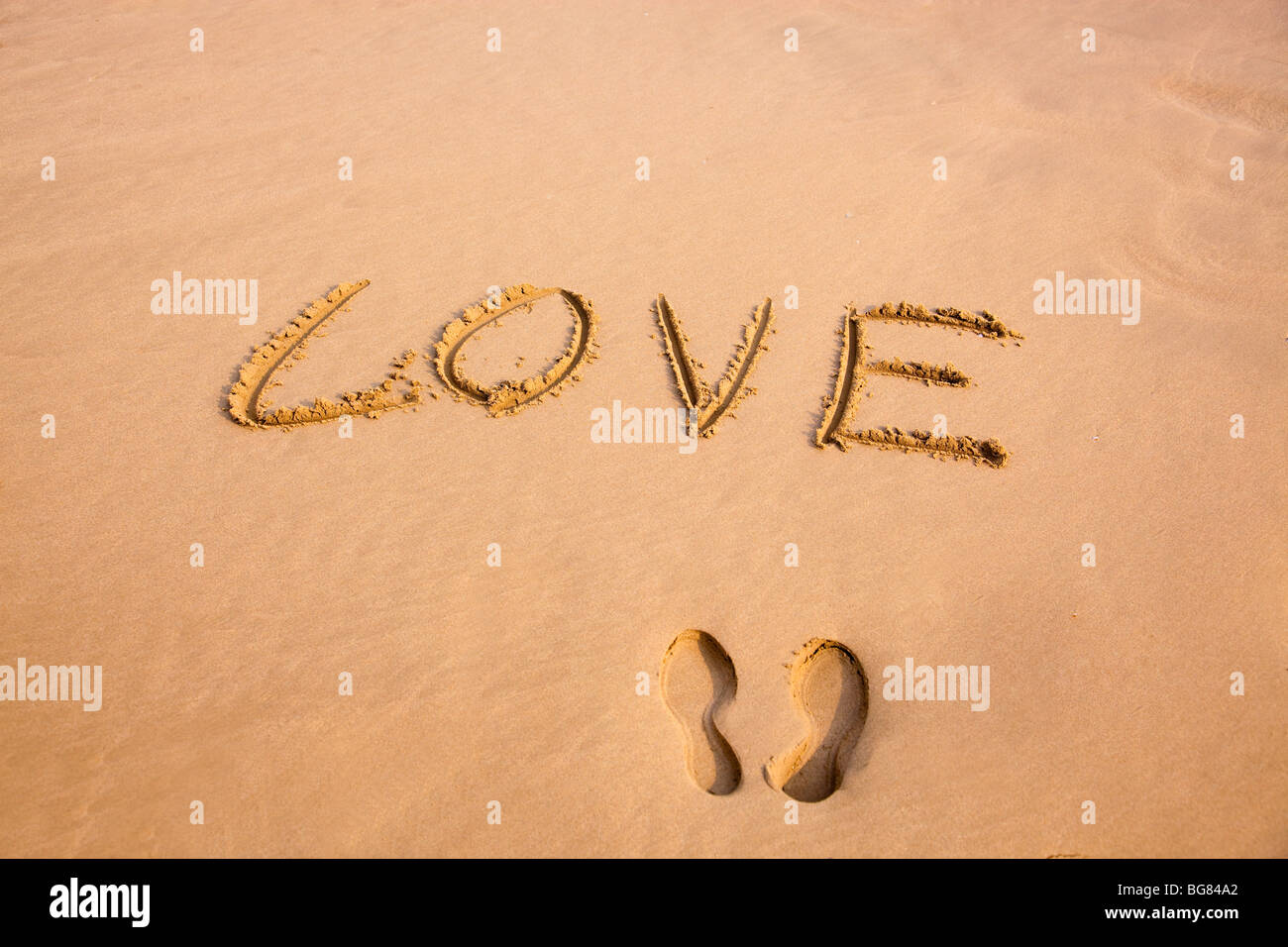 Footprint e amore della scrittura di sabbia su una spiaggia Foto Stock