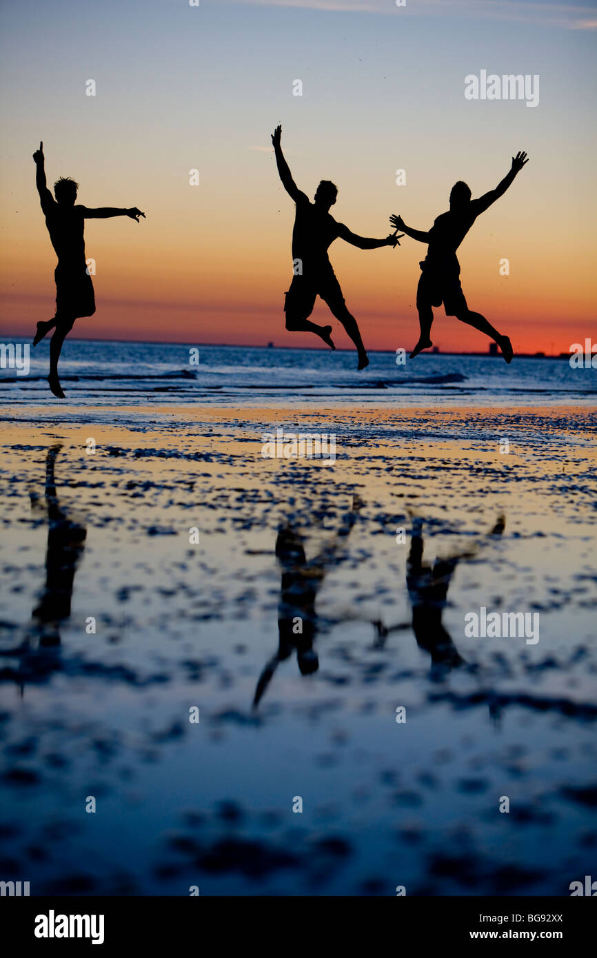 I giovani adulti salto alto durante una passeggiata sulla spiaggia. Foto Stock