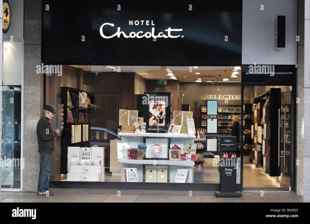 Un uomo in piedi al di fuori del hotel Chocolat, lusso pasticcieri, 'Coltivatore di cacao & Chocolatier', su Victoria Street, Londra, Regno Unito. Foto Stock