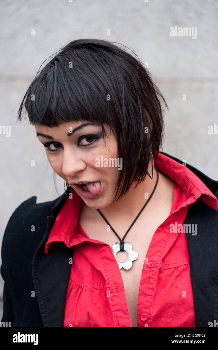Giovane donna con incollaggio di perforazione la sua lingua fuori di Londra, Inghilterra, Regno Unito Foto Stock