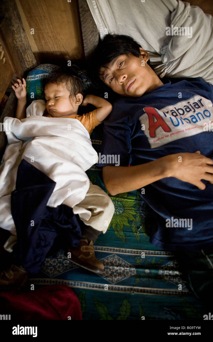 Un uomo sta sveglio con suo figlio che dorme in Puerto Belen, una delle baraccopoli a Iquitos in Perù il bacino amazzonico. Foto Stock