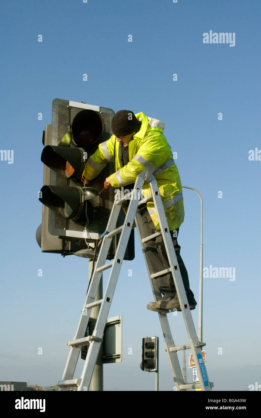 Un operaio che fissa una serie di semafori Foto Stock