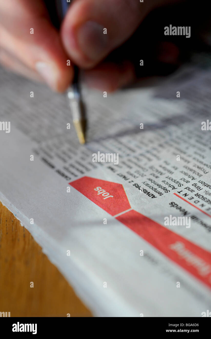 Una persona giovane reti a strascico per la carta locale in cerca di un lavoro nella sezione classificati. Foto da Jim Holden. Foto Stock