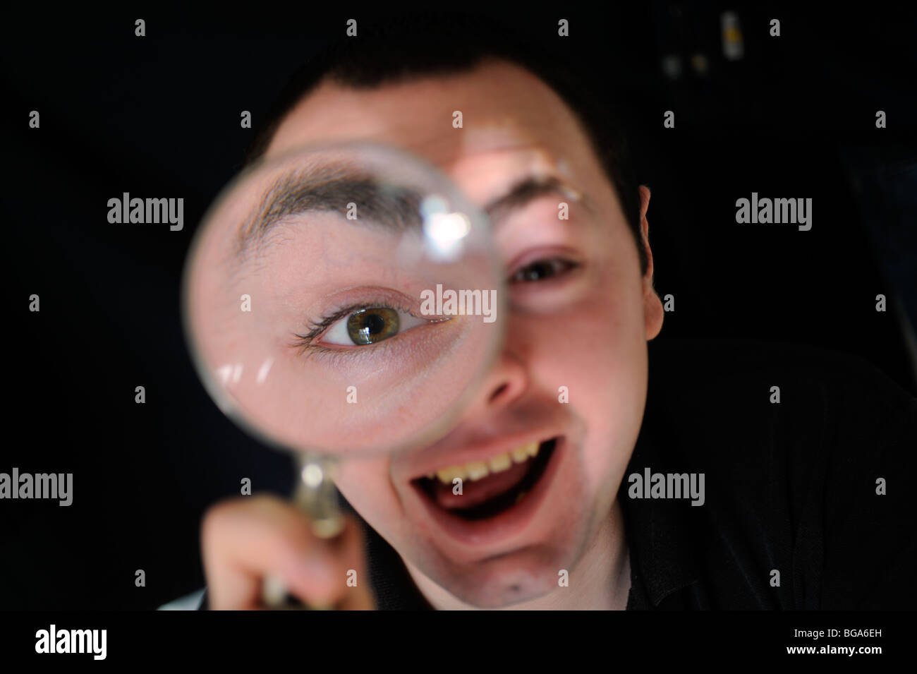 Guardando attraverso una lente di ingrandimento questa persona ha divertimento stravolgere la sua immagine. Foto da Jim Holden. Foto Stock