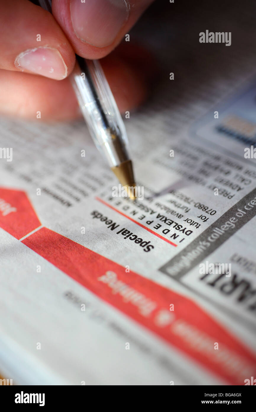 Un giovane job seeker ricerca le carte locali per l'occupazione sotto la voce le esigenze particolari in annunci. Foto Stock
