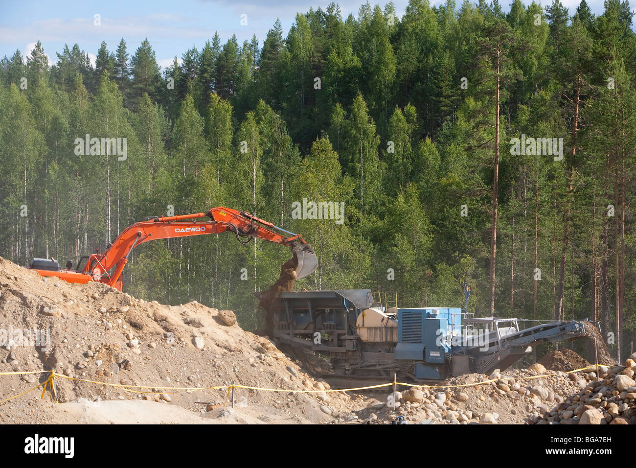 Caricamento di scavo la sabbia e le pietre per il frantumatore / macchina del separatore in una cava di ghiaia , Finlandia Foto Stock